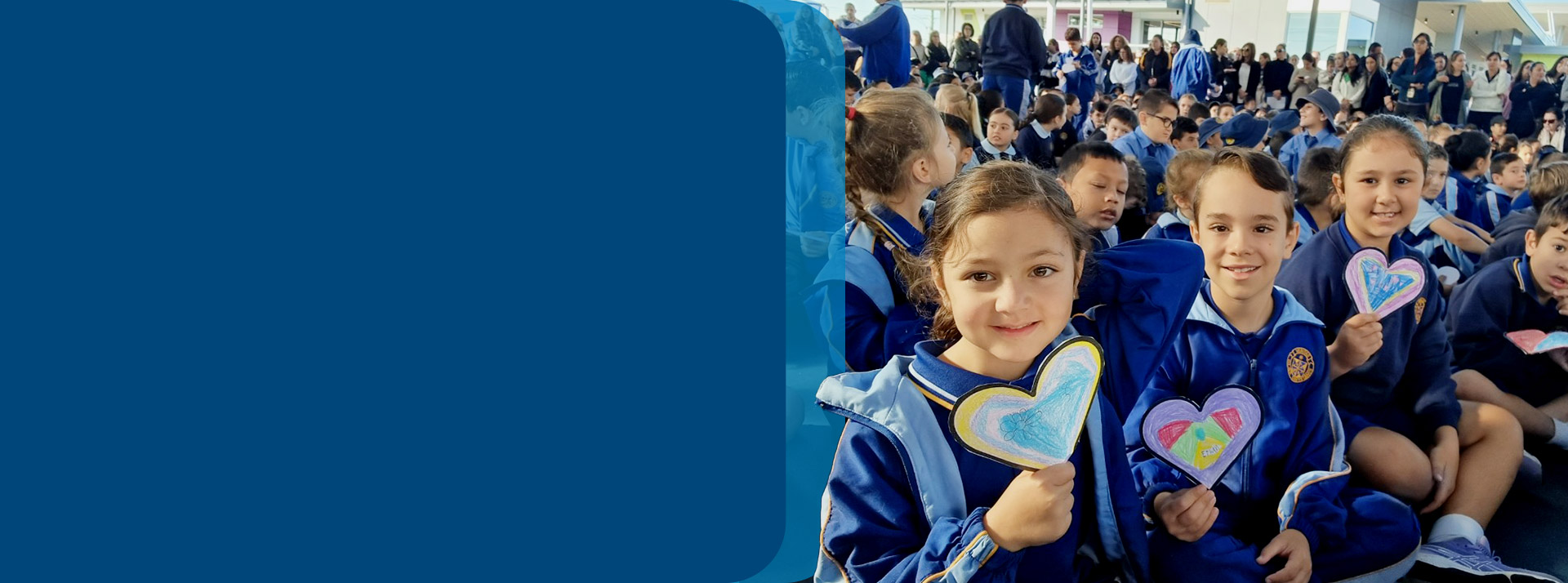 Students holding love heart artwork at assembly at Our Lady Queen of Peace Primary School Greystanes