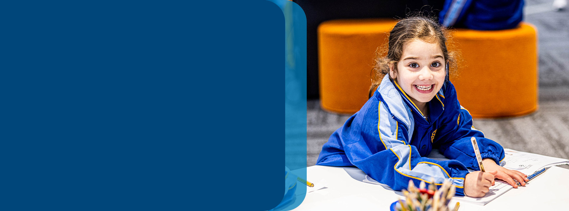 Student smiling at her desk in the classroom at Our Lady Queen of Peace Primary School Greystanes