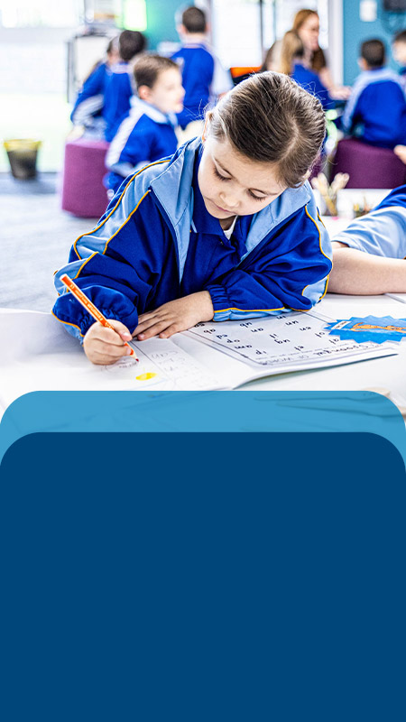 Students writing at their desk in the classroom at Our Lady Queen of Peace Primary School Greystanes