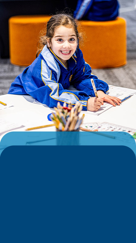 Student smiling at her desk in the classroom at Our Lady Queen of Peace Primary School Greystanes