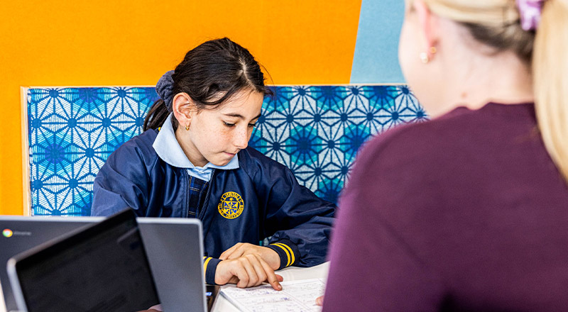 Student learning to read with her teacher in the classroom at Our Lady Queen of Peace Primary School Greystanes