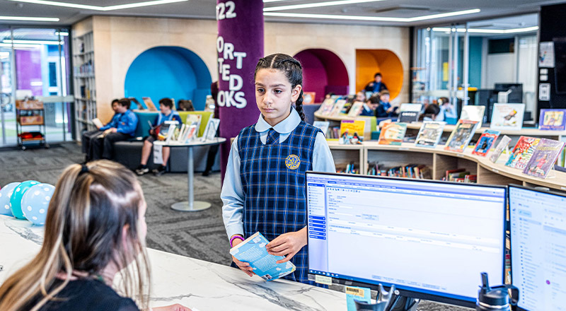 Student borrowing a book from the library at Our Lady Queen of Peace Primary School Greystanes
