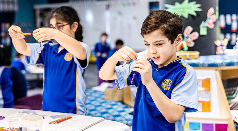 Student threading beads in the classroom at Our Lady Queen of Peace Primary School Greystanes