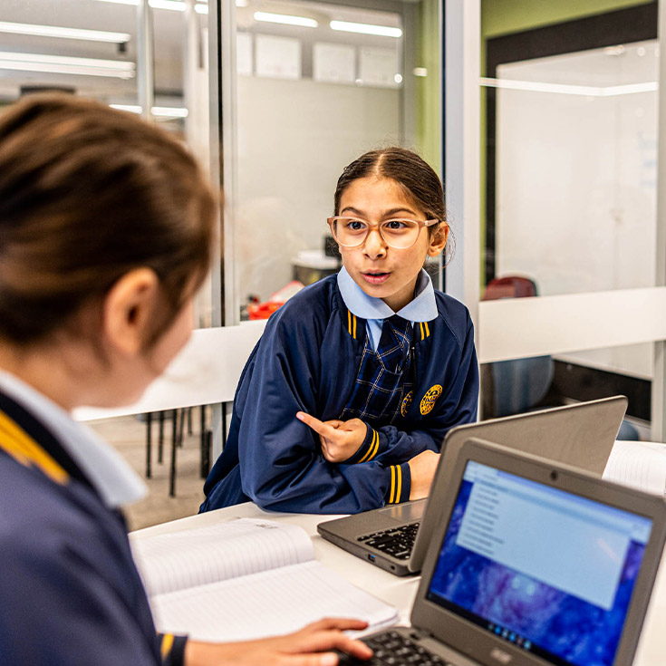 Student speaking with her classmate in the classroom at Our Lady Queen of Peace Primary School Greystanes
