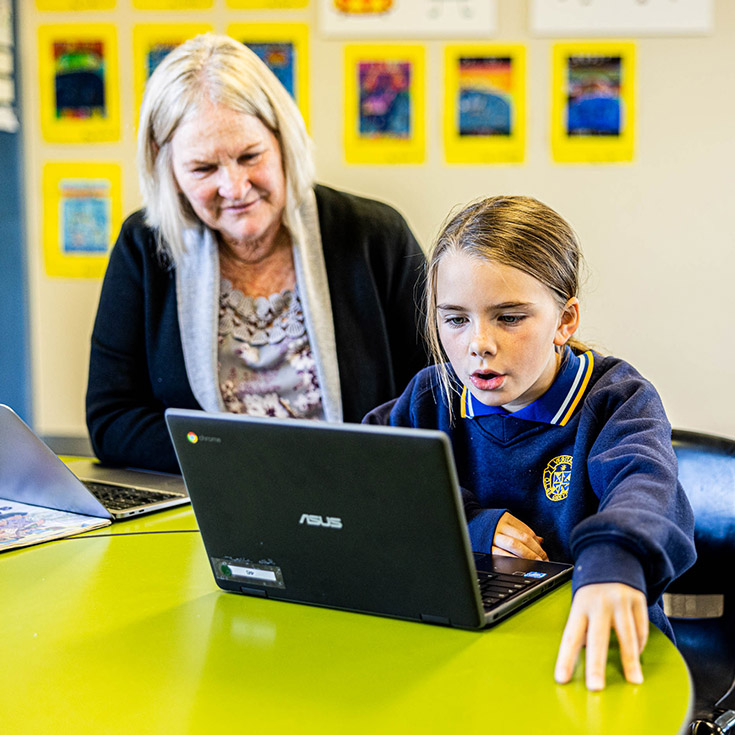 Teacher helping her student in the classroom at Our Lady Queen of Peace Primary School Greystanes